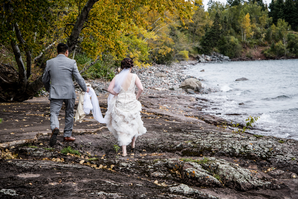 groom holding brides dress as they run