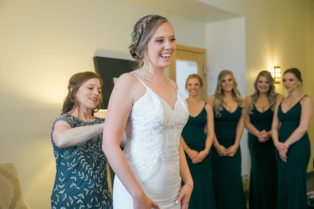 bride getting into her dress with bridesmaids