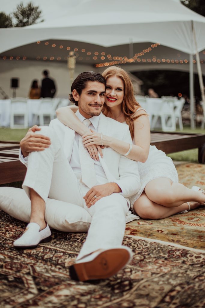 bride and groom sitting on rug outside