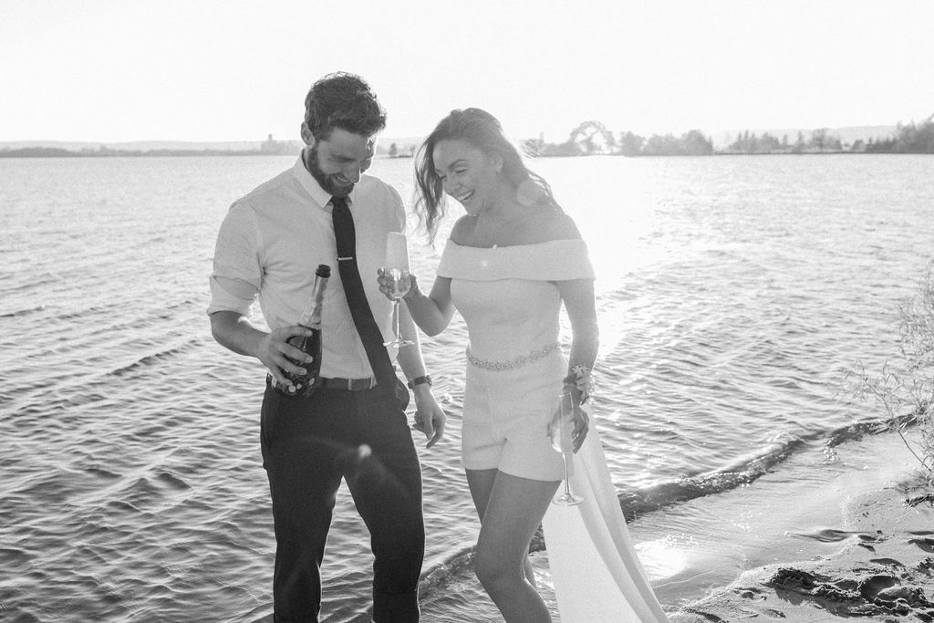 black and white image of bride and groom drinking champagne 