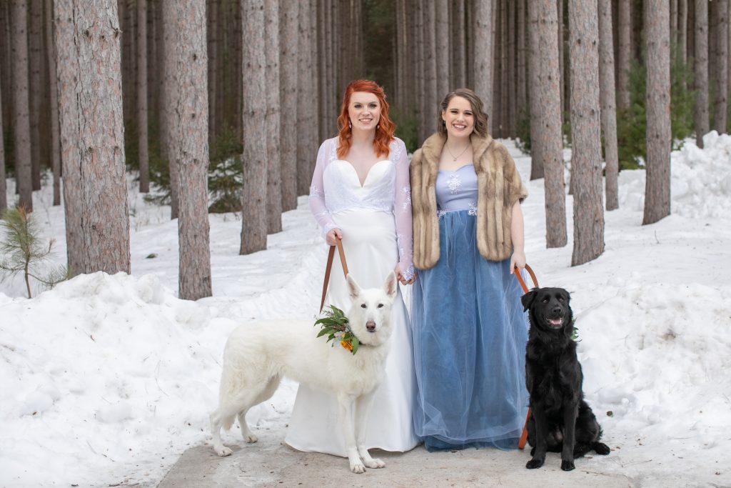 bride and bridesmaid in the snow with dogs