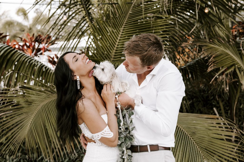 bride and groom laughing with puppy