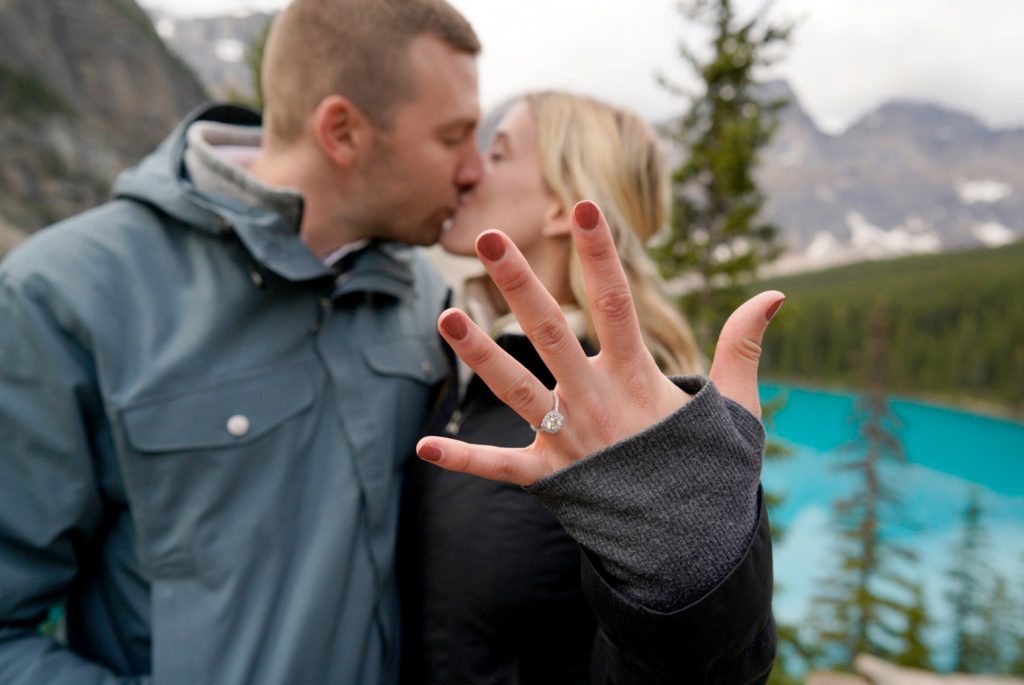 bride and groom kissing and showing off engagement ring