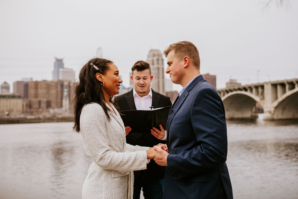 bride and groom and officiant standing by a river