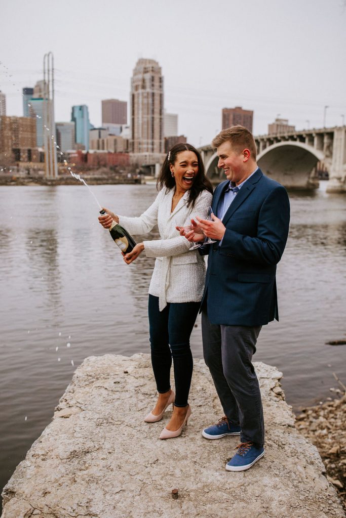 bride and groom popping a bottle of champagne