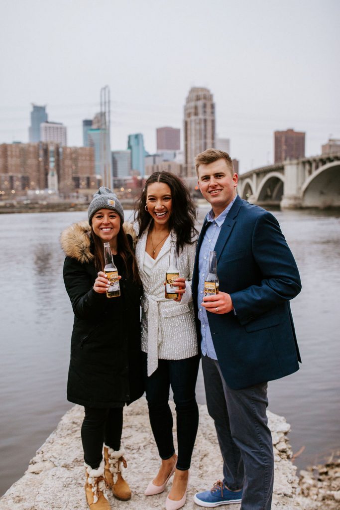 bride, groom and friend smiling in front of river