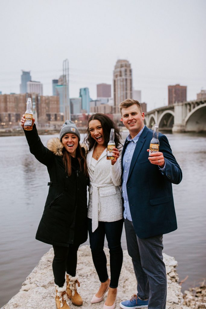 bride, groom and friend celebrating in front of river