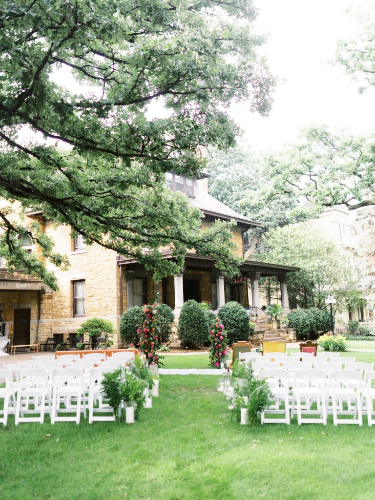 ceremony set up with bright flowers and all white chairs