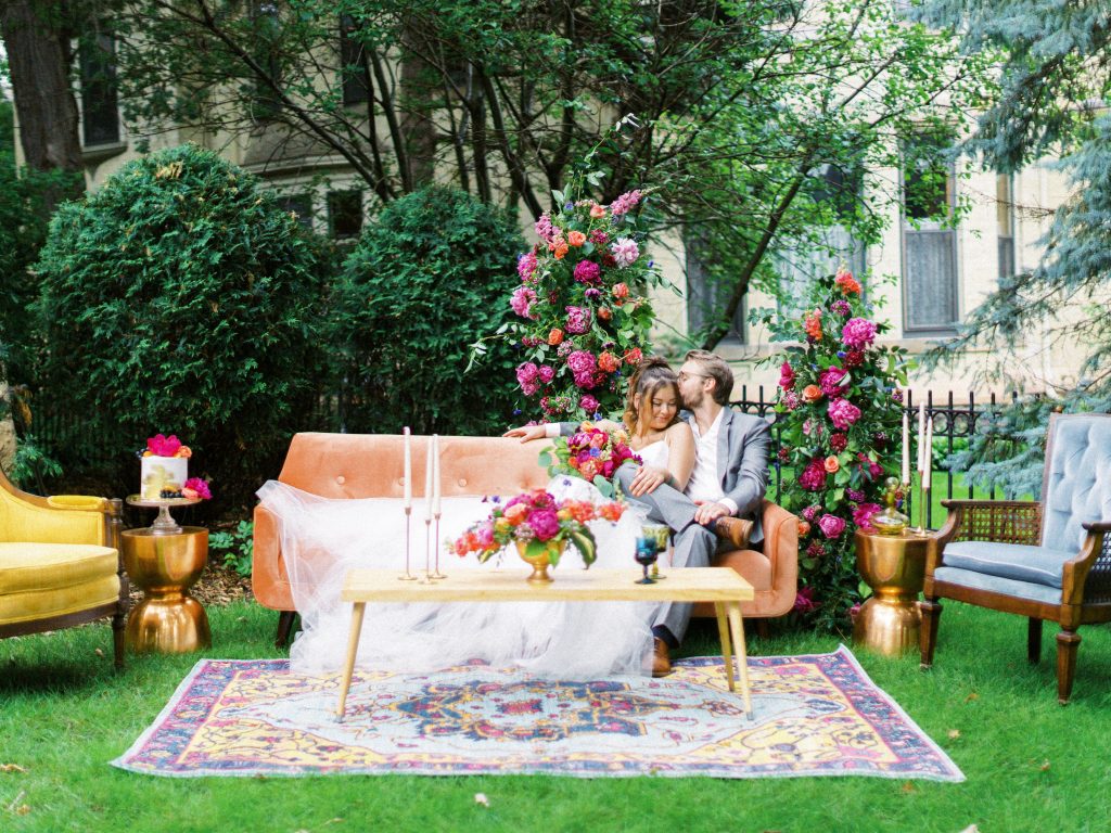 bride and groom sitting outdoors together on bright colored couch