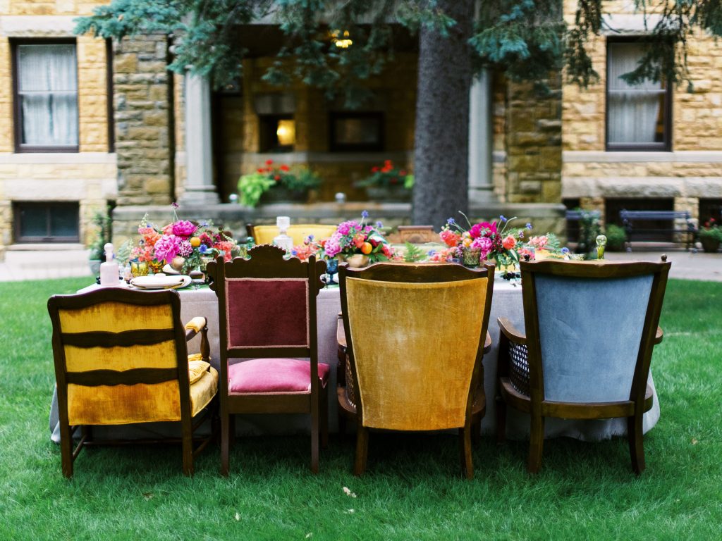 wedding tablescape with bright colored flowers and various colored chairs