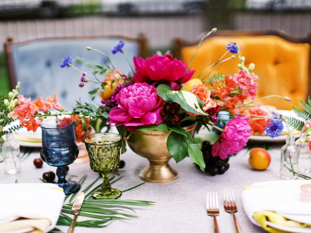 wedding tablescape with bright colored flowers and various colored chairs