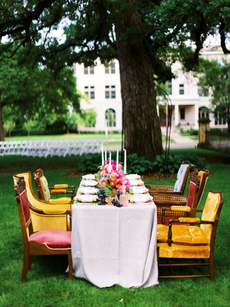 wedding tablescape with bright colored flowers and various colored chairs