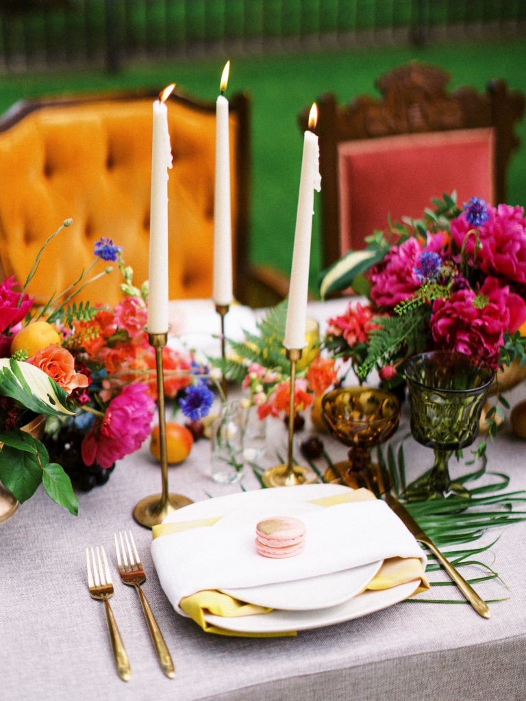 wedding tablescape with bright colored flowers and various colored chairs