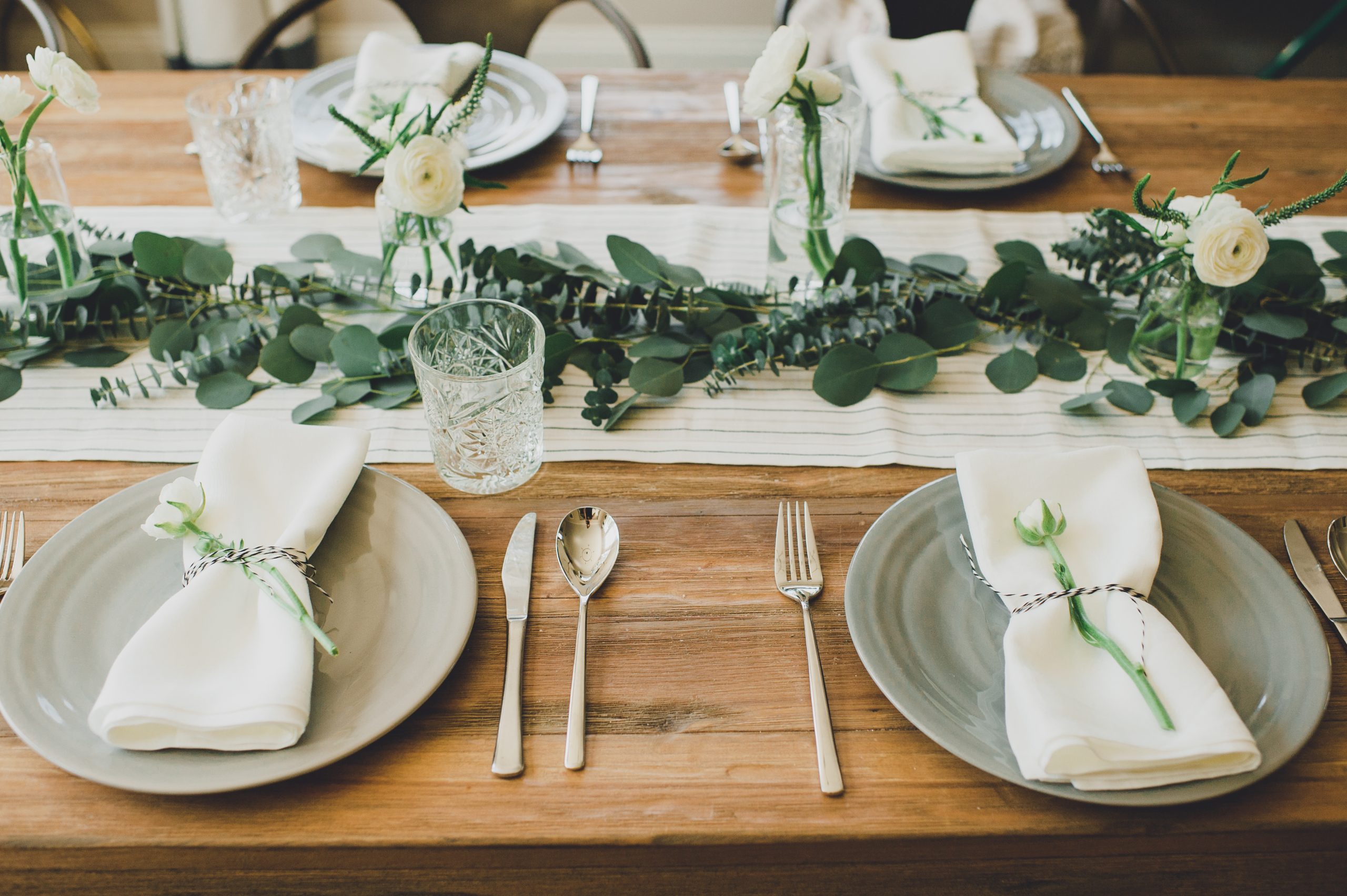 Dinner setting with dinner plates, glasses, flatware and flowers