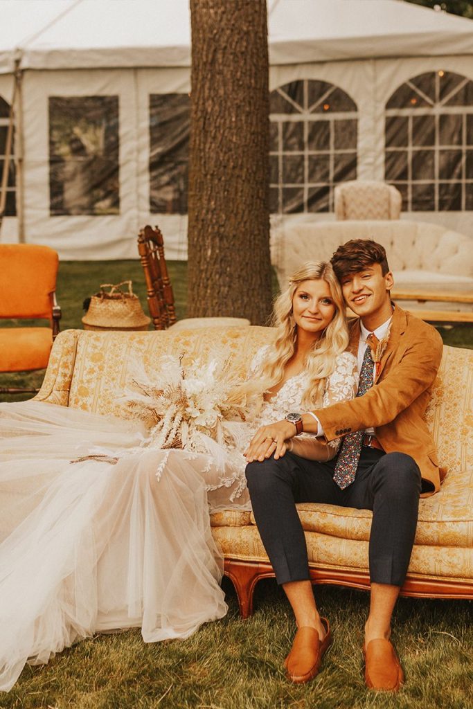 bride and groom sitting on couch outdoors