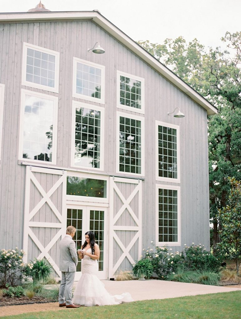 bride and groom reading vows in front of barn