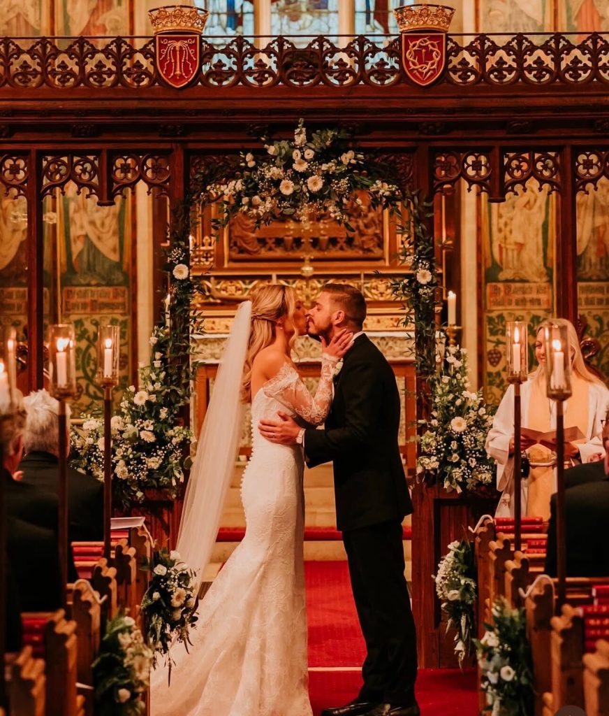 A couple having their first kiss in front of festive florals