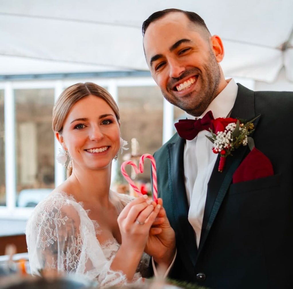 A newlywed couple holding candy canes in the shape of a heart