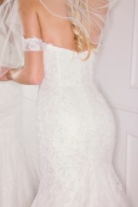 A bride stands in front of a mirror wondering "What does a bride need on her wedding day?"