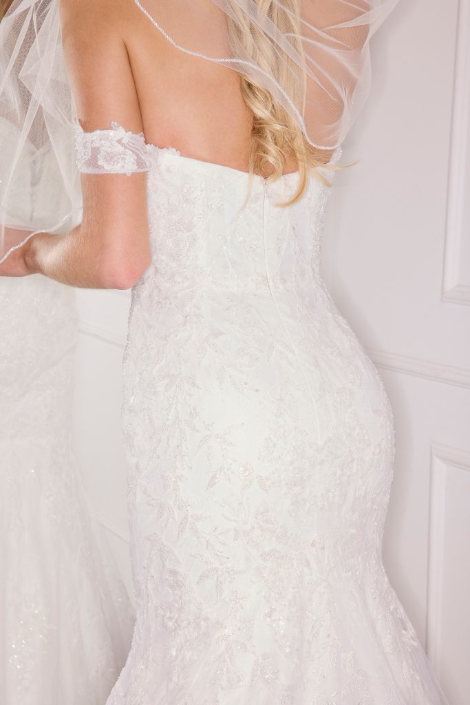 A bride stands in front of a mirror wondering "What does a bride need on her wedding day?"