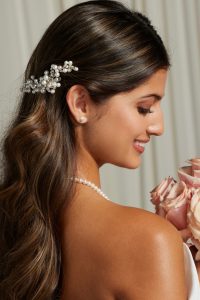 A bride using hair accessories to style her minimalist wedding dress
